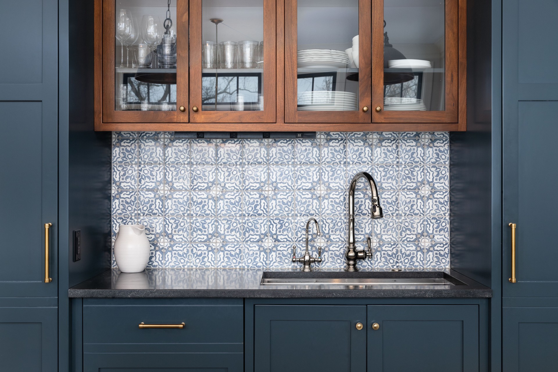 A kitchen with blue cabinets and mosaic tile backsplash.